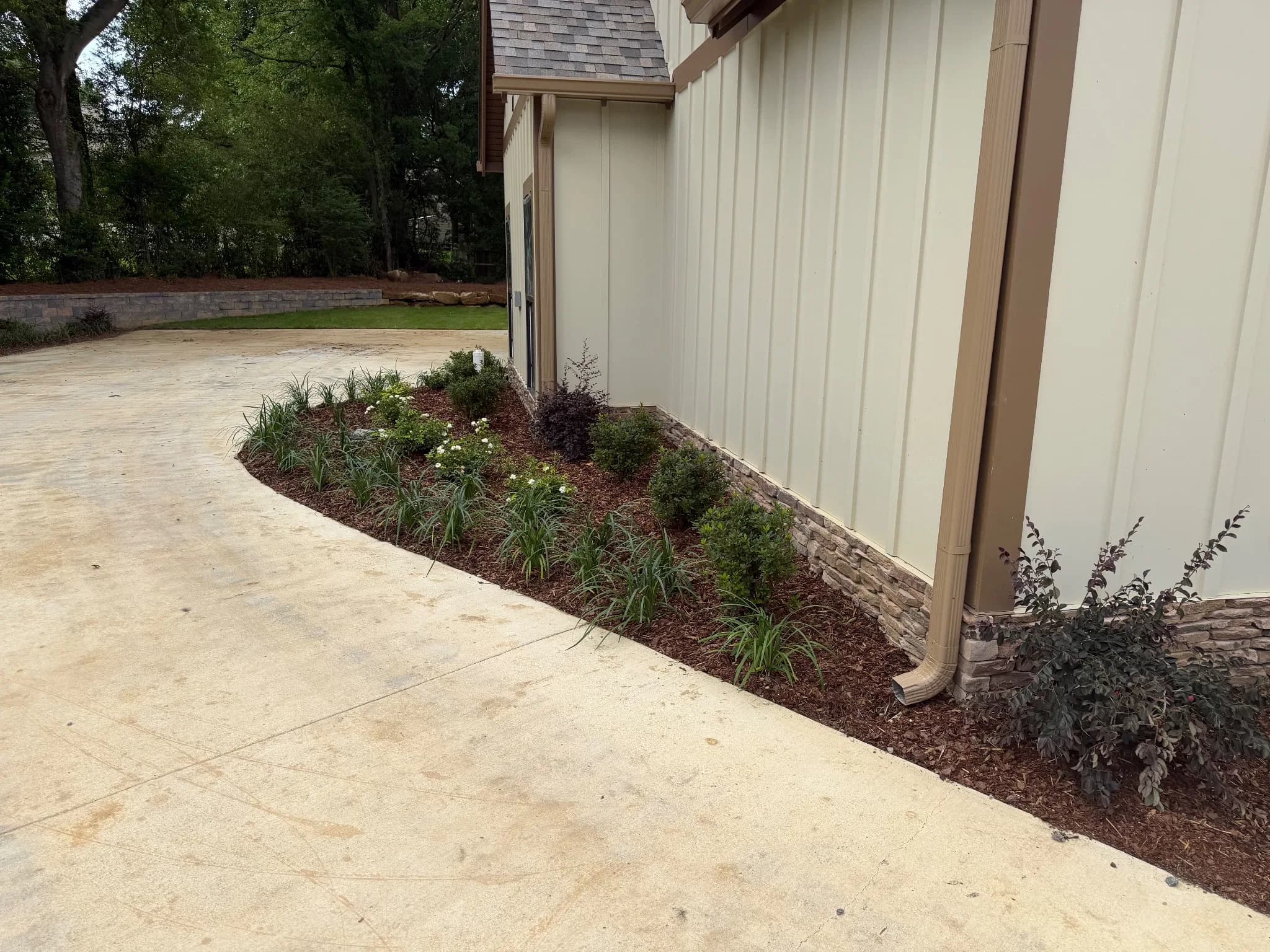 Completed landscaping with plants and mulch along a curved pathway.