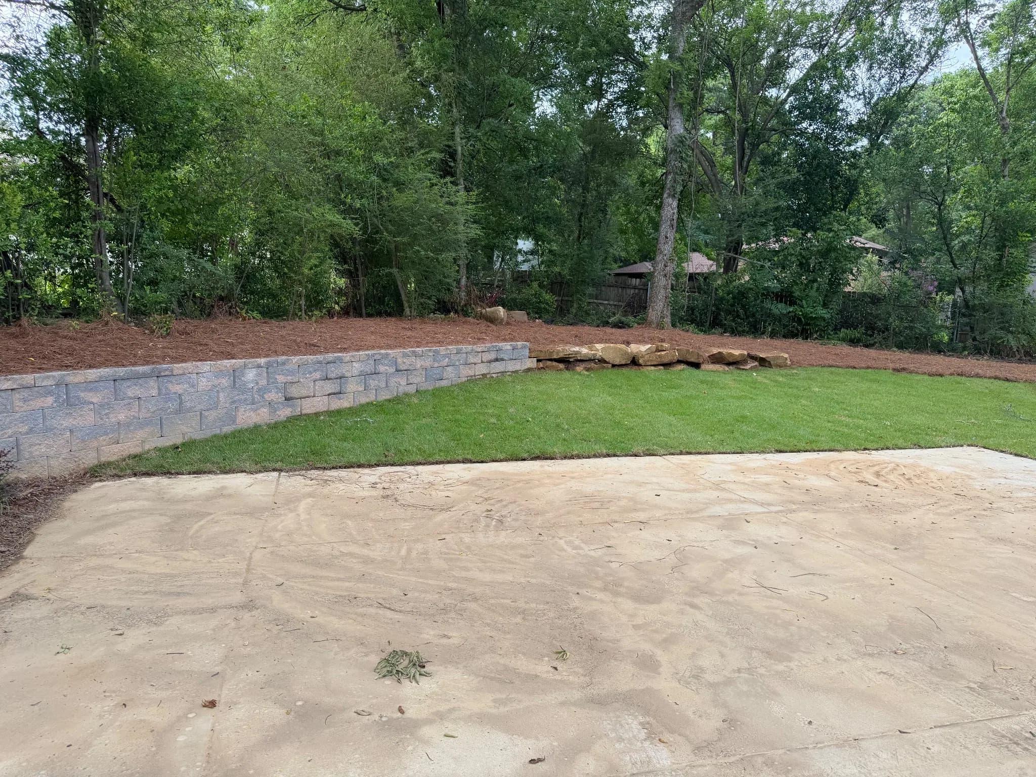 Landscaped yard with grass, stone wall, and cleared area.
